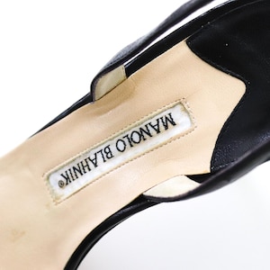 May include: Close-up of the inside of a black leather heeled shoe with a white label that reads "MANOLO BLAHNIK".