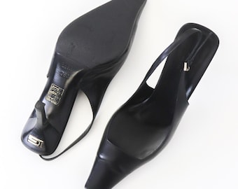 May include: A pair of black leather slingback heels with a square toe and a stiletto heel. The heels have a gold label on the bottom that says "Gino 350 Made in Italy".