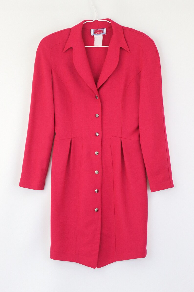 May include: A long-sleeved, button-up dress in a vibrant pink hue. The dress has a classic collar and a fitted silhouette.