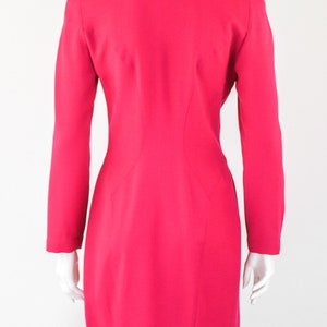 May include: A bright pink blazer with long sleeves and a single button closure. The blazer is fitted and has a slightly flared skirt.