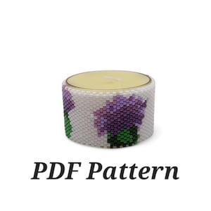 Puede incluir: Un portavelas de cuentas blancas con un diseño floral morado y verde. El portavelas está vacío y listo para sostener una vela de té. Patrón PDF.