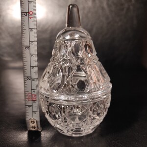 Pu&ograve; includere: Un vaso di vetro trasparente a forma di pera con un coperchio. Il vaso ha un motivo a forma di diamante.