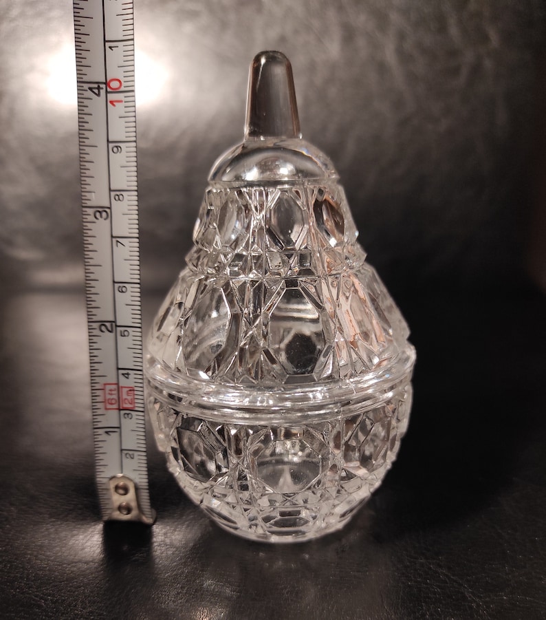 Pu&ograve; includere: Un vaso di vetro trasparente a forma di pera con un coperchio. Il vaso ha un motivo a forma di diamante.