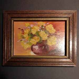 May include: A framed painting depicting a still life with a bunch of yellow roses in a purple vase. The background is a warm orange colour.