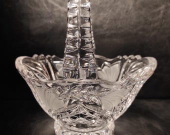 May include: A clear glass basket with a cut crystal design and a handle. The basket is perfect for holding small items like candy or fruit.