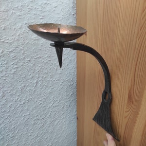 Vintage handmade forged wall candlestick made of iron and brass.