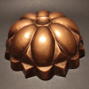 Op de afbeelding: Een koperkleurige, vintage taartvorm met een gegolfde rand en een bloemvormig ontwerp. De vorm is gemaakt van metaal en heeft een glanzende afwerking.