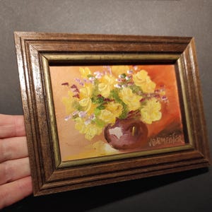 May include: A framed painting of a yellow flower bouquet in a purple vase. The painting is signed "J. Burmeister".