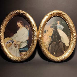 May include: Two oval-shaped gold frames with vintage portraits. One frame features a woman in a white dress, seated with a hat. The other frame depicts a woman on a black horse. The frames have ornate, textured edges.