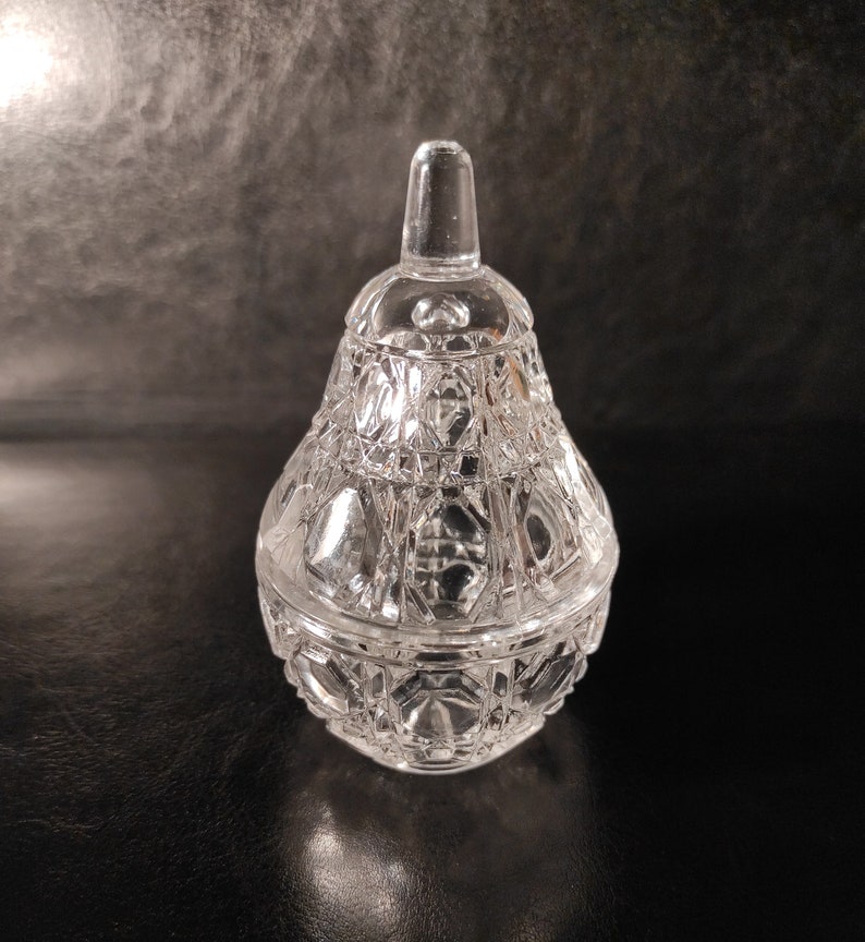 Pu&ograve; includere: Un vaso di vetro trasparente a forma di pera con un coperchio. Il vaso ha un design in vetro tagliato.