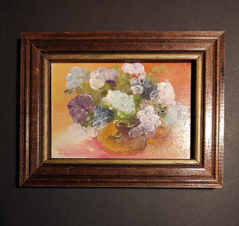 May include: A framed oil painting depicting a bouquet of purple, white and blue flowers in a brown vase. The flowers are set against a warm orange background.