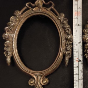 Puede incluir: Dos marcos de fotos ovalados adornados con un diseño floral. Los marcos son de metal y tienen un acabado dorado. Los marcos miden aproximadamente 10 cm de diámetro.