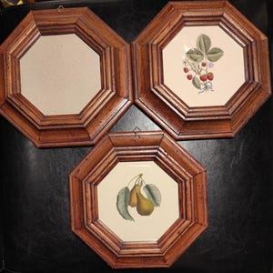 Może przedstawiać: Trzy ośmiokątne drewniane ramki na zdjęcia. Jedna ramka jest pusta, a dwie pozostałe zawierają botaniczne ilustracje truskawek i gruszek. Ramki mają ciemnobrązowe wykończenie i są gotowe do zawieszenia.