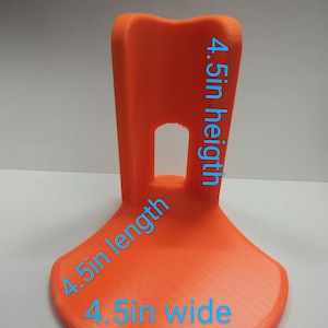 May include: Orange plastic stand with a 4.5 in wide base, 4.5 in length, and 4.5 in height.