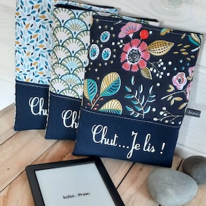 Peut inclure: Trois housses en tissu à motifs différents pour une liseuse. Les housses sont noires avec des motifs floraux, géométriques et de feuilles colorés. Le texte "Chut...Je lis!" est brodé en bas d'une housse.