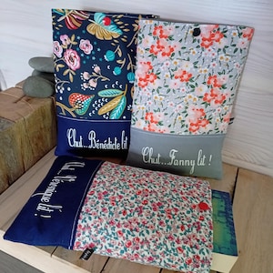 May include: Three fabric book sleeves with floral patterns and text. One sleeve is navy blue with a floral design and the text "Chut... B&eacute;n&eacute;dicte lit!". Another is gray with orange flowers and the text "Chut... Fanny lit!". The third is floral with a red button.