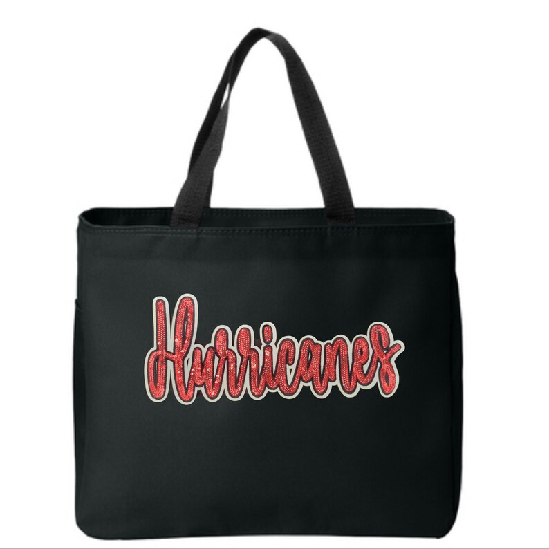 May include: Black tote bag featuring the word "Hurricanes" in red, glittery script. The bag has black handles and a side pocket. The text is outlined in white.