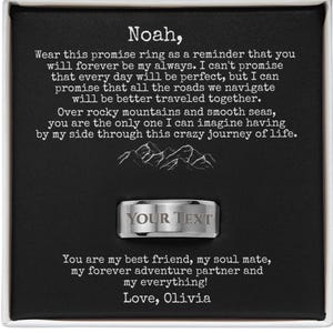 May include: A silver promise ring with the text "YOUR TEXT" engraved on it, presented in a black box with white text. The box contains a heartfelt message about love and commitment, with the name "Noah" at the top.
