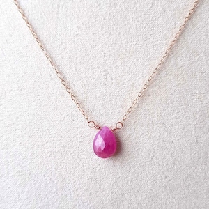 Könnte beinhalten: Eine zarte Halskette aus roségoldener Kette mit einem einzelnen rosa Edelstein-Anhänger.