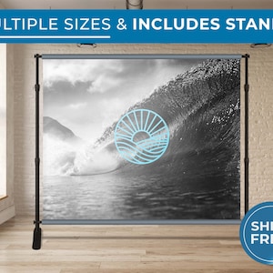 May include: A black and white photo of a wave crashing in the ocean. The photo is printed on a backdrop with a blue and white logo of a sun and waves. The backdrop is attached to a black stand.