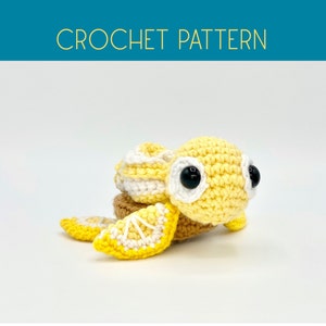 May include: A crocheted yellow and white turtle with black eyes. The turtle has a shell that looks like a lemon.
