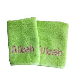 May include: Two lime green towels with the name "Aileah" embroidered in pink on each towel.