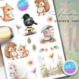 Puede incluir: Una hoja de pegatinas con ilustraciones de acuarela de animales y plantas del bosque. Los dise&ntilde;os incluyen un zorro, un erizo, un p&aacute;jaro, un rat&oacute;n y varias flores y setas. El texto "Handmade Sticker Sheet" es visible.