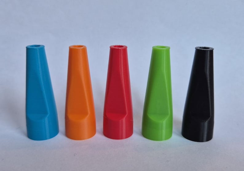 K&ouml;nnte beinhalten: F&uuml;nf farbige, kegelf&ouml;rmige Objekte in einer Reihe. Die Farben sind Blau, Orange, Rot, Gr&uuml;n und Schwarz. Jedes Objekt hat eine hohle Oberseite und eine flache, abgewinkelte Seite. Wahrscheinlich dekorative oder funktionale Artikel.