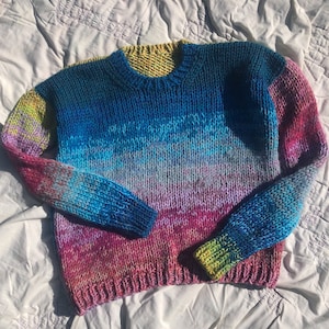Puede incluir: Un suéter de punto colorido con un degradado de rosa, azul y amarillo.