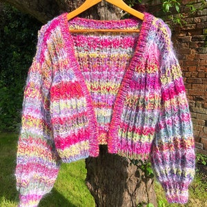 May include: A colorful striped cardigan with a fuzzy texture. The cardigan is cropped and has long sleeves.