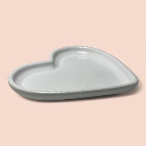 Pu&ograve; includere: Un piatto in ceramica bianco a forma di cuore con una superficie leggermente strutturata. Il piatto ha una profondit&agrave; ridotta e un interno liscio e lucido. La forma a cuore &egrave; ben definita, rendendolo un pezzo decorativo.