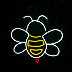 Puede incluir: Contorno de abeja de ne&oacute;n blanco con rayas amarillas y un aguij&oacute;n rojo. La abeja est&aacute; sobre un fondo verde oscuro.