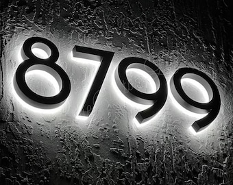 May include: Black illuminated house numbers 8799 mounted on a textured wall.