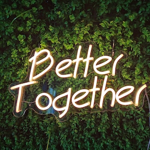 May include: Neon sign with the words "Better Together" in white letters against a green leafy background.