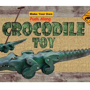 May include: A green crocodile push toy with wheels. The toy is on a brown and tan rug with the words "Make Your Own Push-Along Crocodile Toy" and a yellow warning sign that says "Danger Crocodiles No Swimming".
