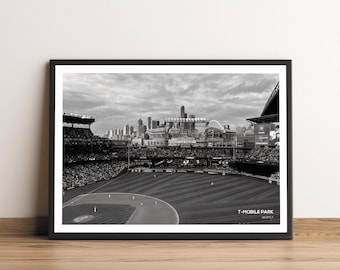 Może przedstawiać: Czarno-białe zdjęcie stadionu baseballowego, T-Mobile Park w Seattle, z tłumem ludzi na trybunach i panoramą miasta w tle.