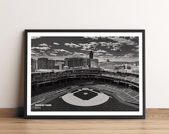 Puede incluir: Una fotografía aérea en blanco y negro del Fenway Park en Boston, Massachusetts. El campo de béisbol es visible en el centro de la imagen, rodeado por las gradas del estadio. El horizonte de la ciudad es visible en el fondo.