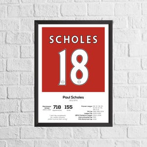 May include: A red and white framed poster with the name "SCHOLES" and the number "18" in white. The poster features the name "Paul Scholes" and his birthdate, "16/11/1974".  The poster also includes statistics for his career with Manchester United, including appearances and goals.