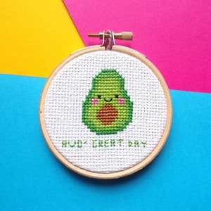 May include: A white embroidery hoop with a green avocado design and the text "Avo' Great Day".