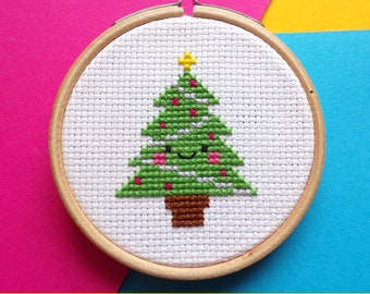 May include: A cross-stitch pattern of a smiling Christmas tree with red and white ornaments in a wooden embroidery hoop.  PDF Digital Download.