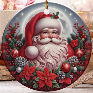 May include: A round ceramic Christmas ornament featuring a detailed illustration of Santa Claus with a white beard and red hat, surrounded by a festive wreath of red poinsettias, pine cones, holly berries, and green pine needles, hanging by a gold cord.