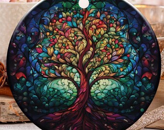 May include: A round Christmas ornament featuring a colorful tree design. The tree has a vibrant array of colors, including red, yellow, green, and blue. The ornament hangs from a gold string. Other holiday decorations are in the background.