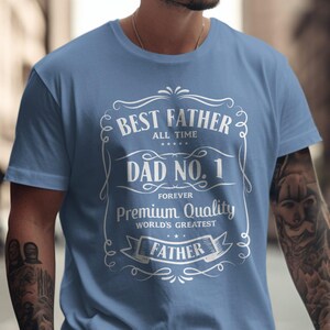 May include: Light blue t-shirt with the text "Best Father All Time Dad No. 1 Forever Premium Quality World's Greatest Father" in a white decorative design. The shirt is made of a soft material.