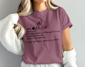 Puede incluir: Camiseta de color malva con la palabra "mother" en escritura cursiva, un corazón y una definición. La definición incluye frases como "ojos en la nuca" y "coordinadora del caos".