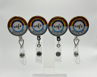 Può includere: Quattro porta badge retrattili a tema arcobaleno con il testo "You are safe with me" su ciascuno. I porta badge sono su uno sfondo bianco.