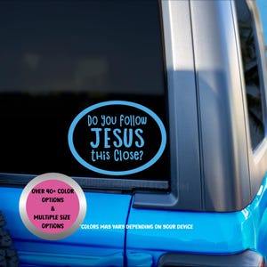May include: A blue oval car decal with the text "Do you follow JESUS this Close?" in a handwritten style font. The decal is on a black background, with a pink circle in the lower left corner that says "OVER 40+ COLOR OPTIONS & MULTIPLE SIZE OPTIONS".