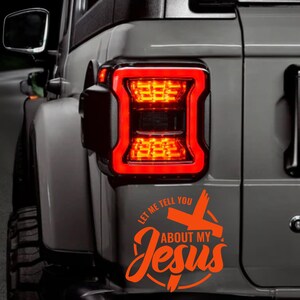 May include: Orange vinyl decal sticker with the text "Let me tell you about my Jesus" and a cross in a circle on a gray car.