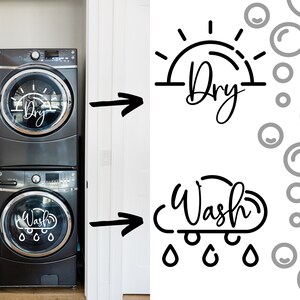 May include: A black and silver stacked washer and dryer set with a white decal on the front of each appliance. The dryer decal features a sun with the word "Dry" written below it. The washer decal features a cloud with the word "Wash" written inside it and raindrops below it.