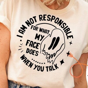 Könnte beinhalten: Ein weißes T-Shirt mit einer schwarzen Grafik, auf der steht "Ich bin nicht verantwortlich für das, was mein Gesicht tut, wenn du sprichst". Die Grafik zeigt einen Geist mit einem tropfenden Gesicht.