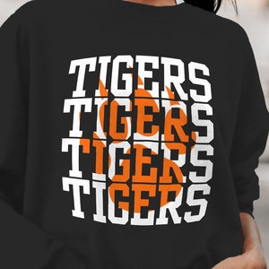May include: Black sweatshirt with a white graphic of the word "TIGERS" repeated four times. An orange paw print is centered in the graphic.